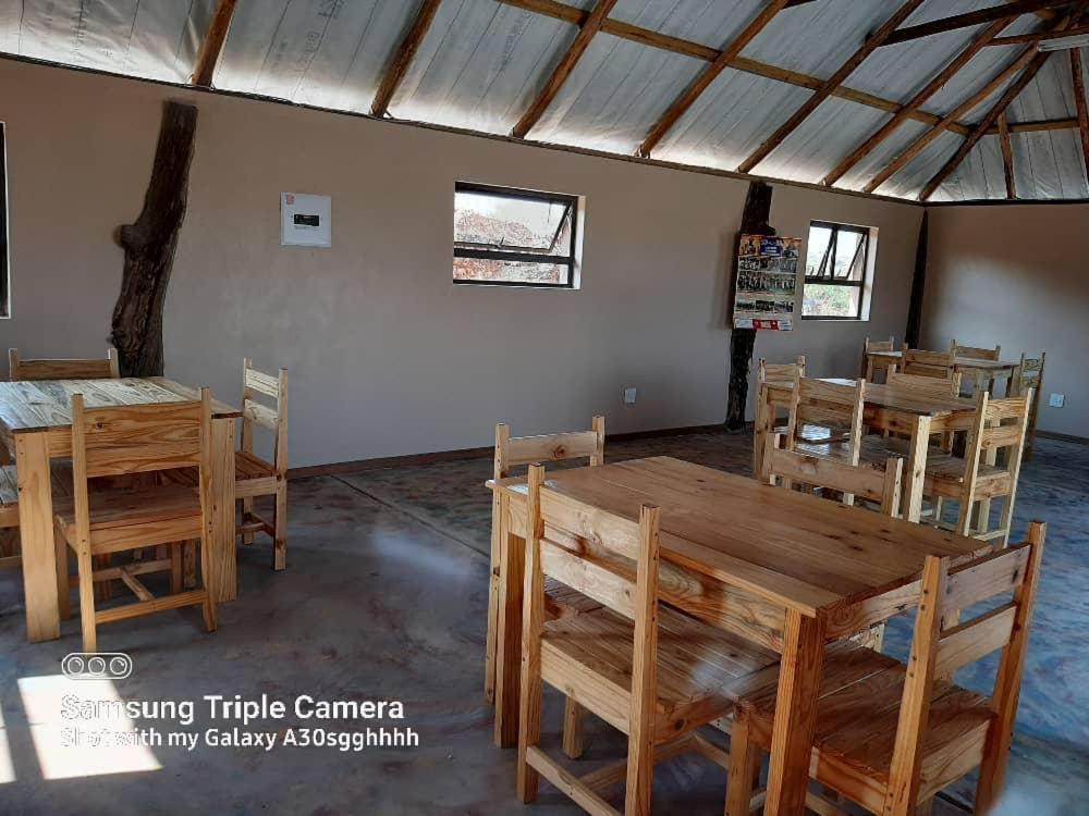 comedor con mesas y sillas de madera en Inkwazi Getaway Lodge en Manzini