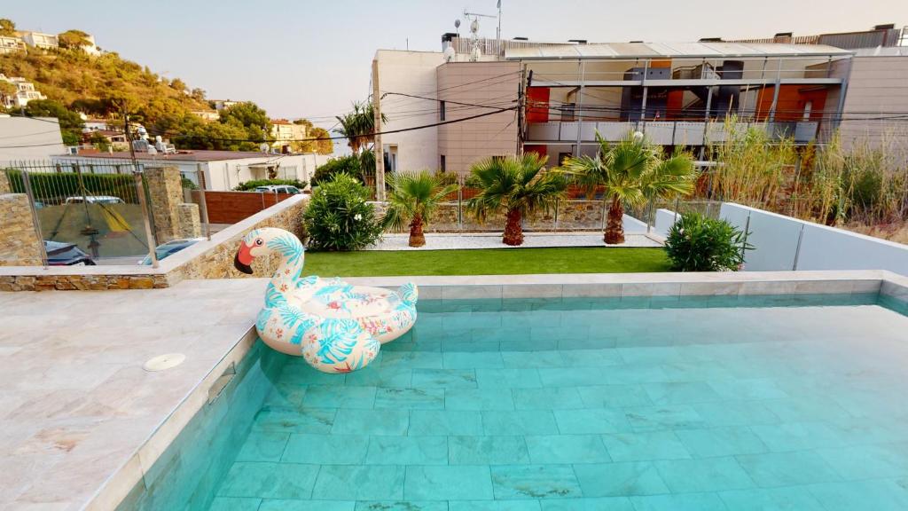 a swimming pool with a swan seat next to a house at Maison, piscine, plage, commerce restaurant in Roses