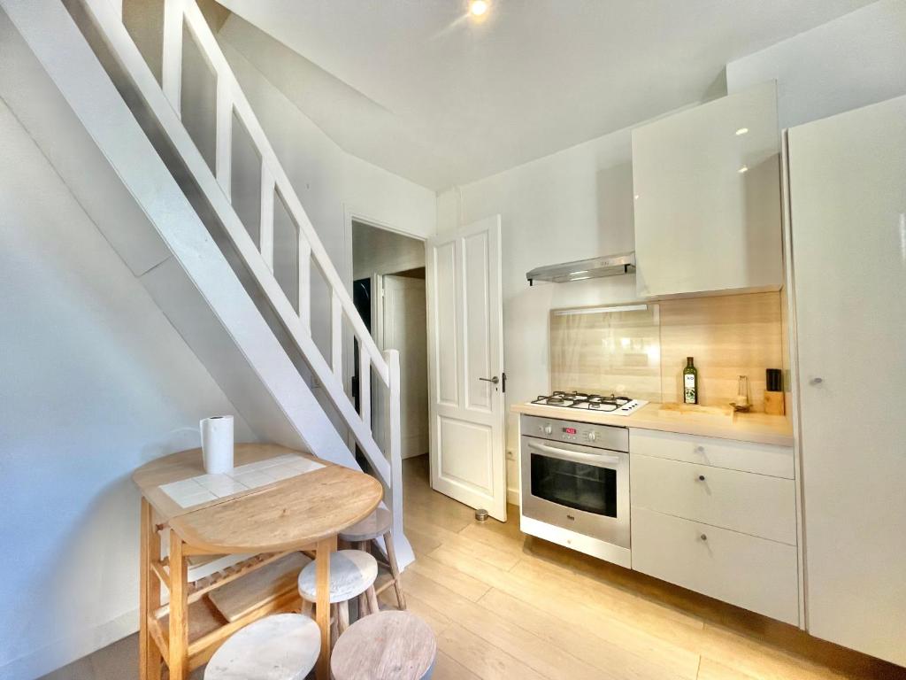 a kitchen with white cabinets and a table and a stove at La Marjolette by Welcome to Cannes in Cannes