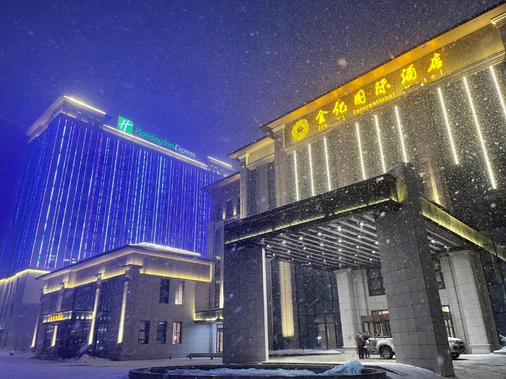 Kurgash的住宿－霍尔果斯金亿国际酒店，雪地中的一座建筑,上面有街道标志