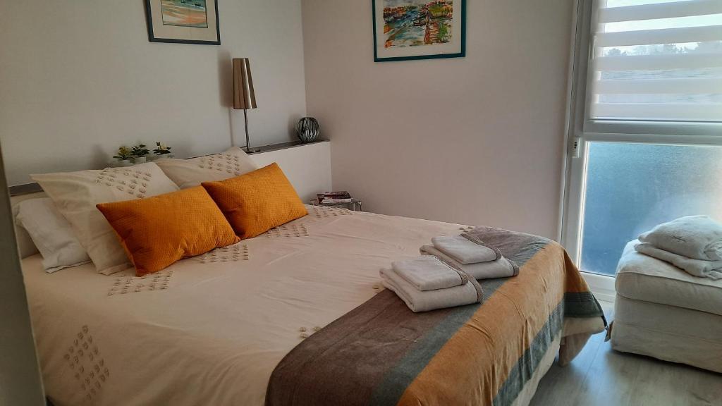 una camera da letto con un letto con cuscini arancioni e una finestra di Dune a La Teste-de-Buch