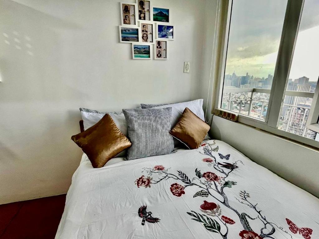 ein Schlafzimmer mit einem Bett mit einem Fenster und einer Bettdecke mit Blumen in der Unterkunft JC Condo, SMDC Green Malate Taft Manila in Manila