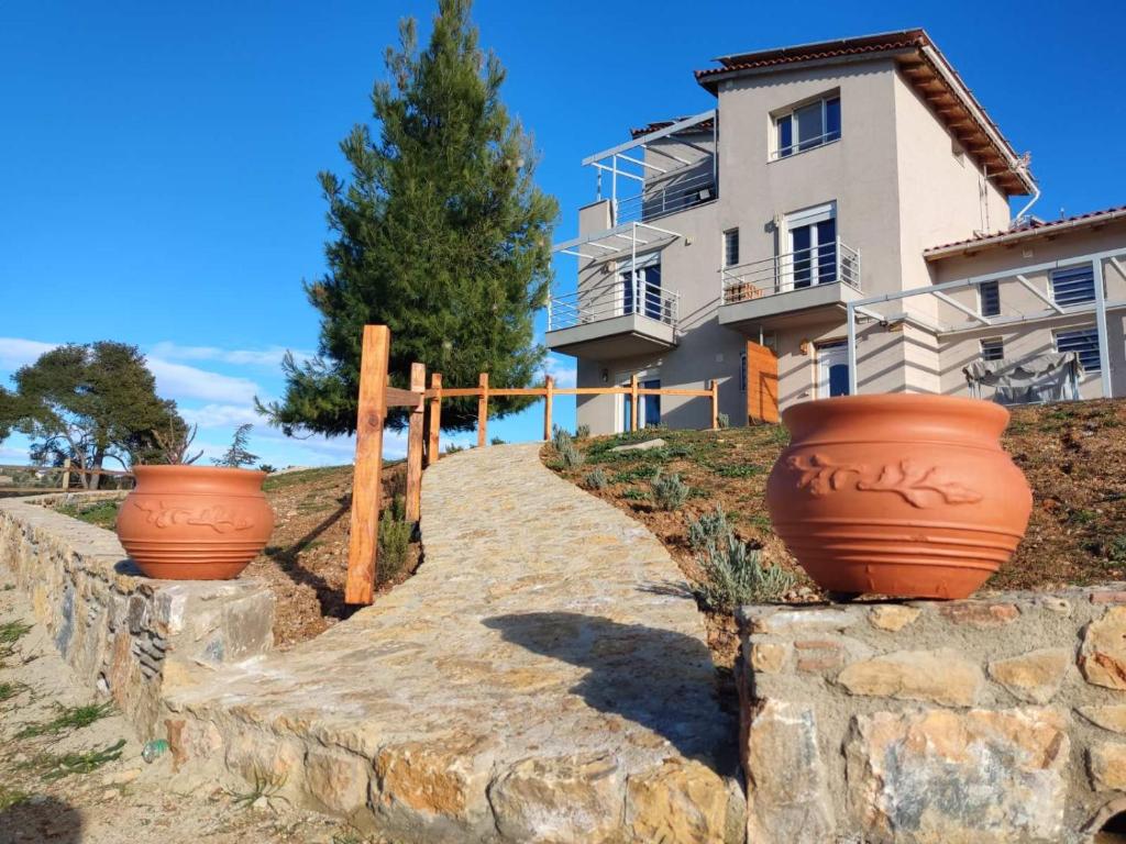 tres grandes ollas de arcilla en una pared de piedra frente a un edificio en EuZoea Country Home, en Kapandrítion