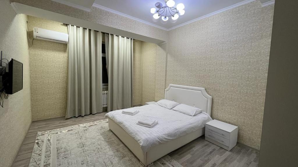 ein Schlafzimmer mit einem weißen Bett und einem Fenster in der Unterkunft Апарт отель Гок Таш in Bischkek