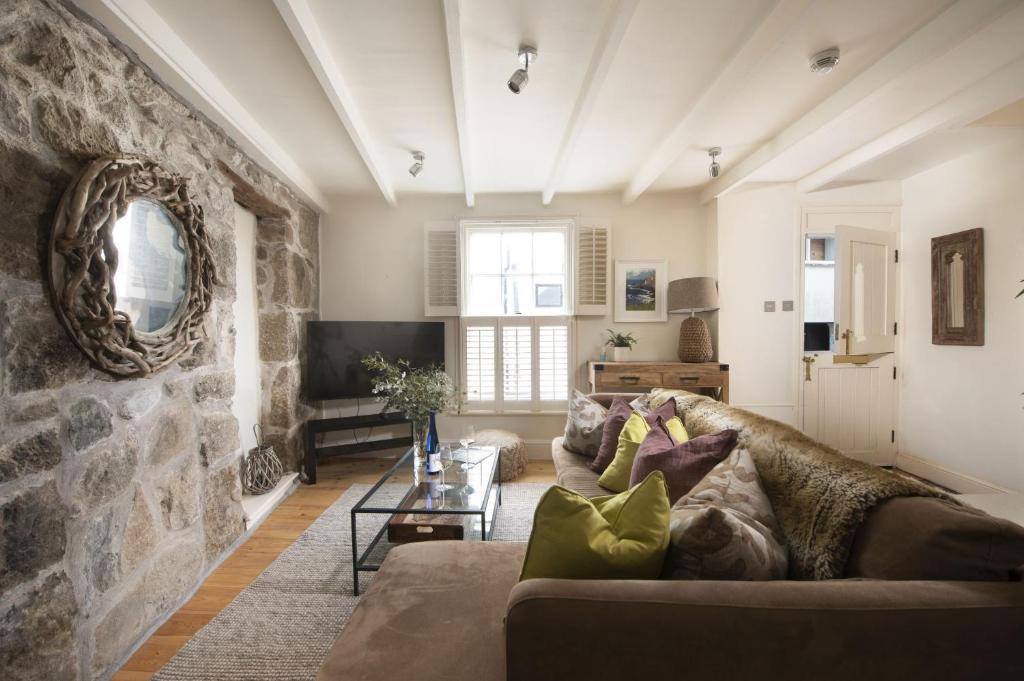 a living room with a couch and a stone wall at Tathra Beach Cottage in St Ives