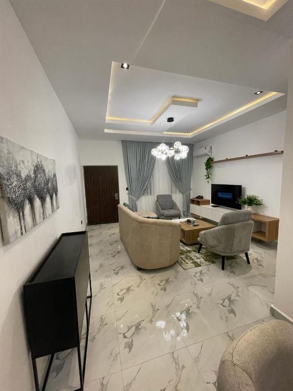 a living room with a couch and chairs and a television at All States Apartments in Abuja