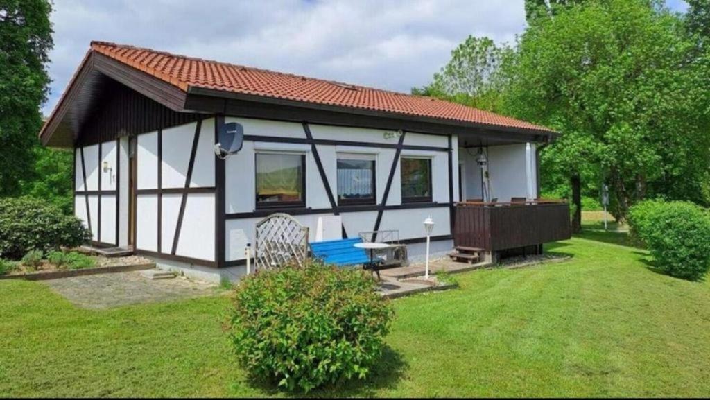 um pequeno chalé branco com um telhado vermelho em Bungalow am Fuße der Wasserkuppe em Dipperz