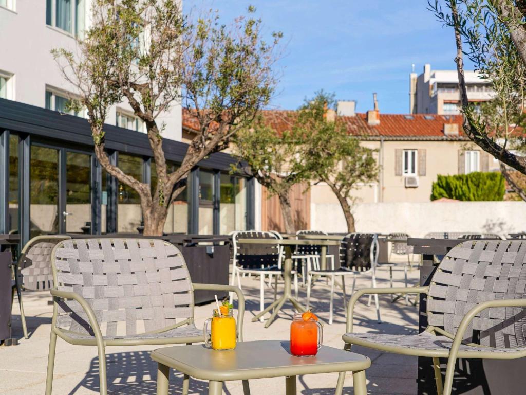 - un ensemble de chaises et de tables sur une terrasse dans l'établissement Mercure Marseille Centre Prado Vélodrome, à Marseille