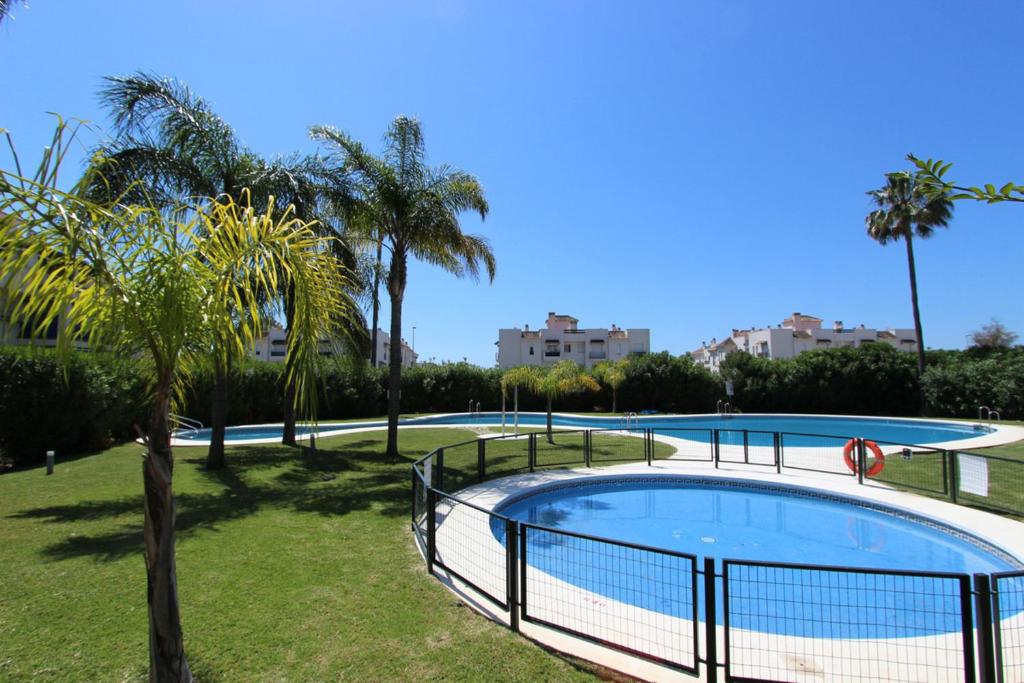 a swimming pool in a park with palm trees at Great 2-Bed Apartment in Nueva Andalucia Marbella in Marbella