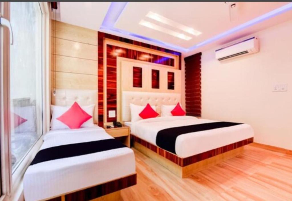 two beds in a hotel room with red pillows at The New Lord Krishna @ New Delhi Railway station in New Delhi