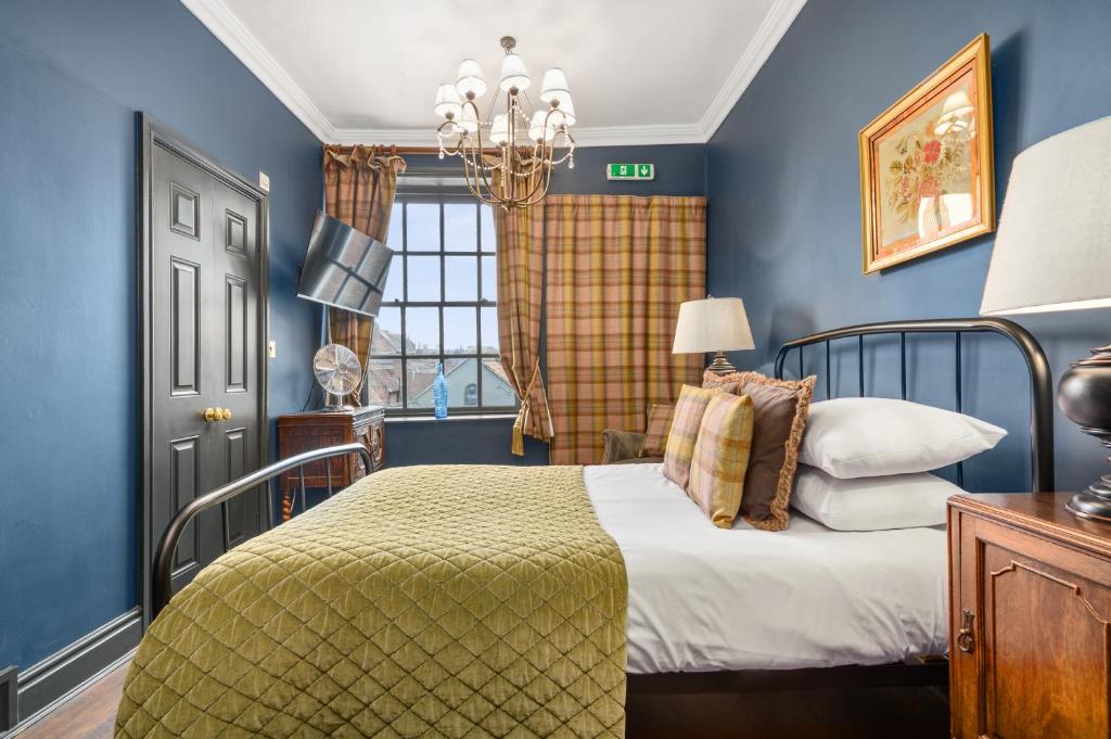 a blue bedroom with a bed and a window at Guy Fawkes Inn in York