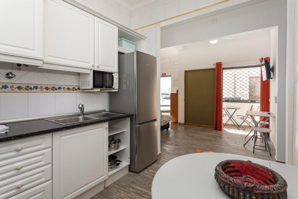 uma cozinha com armários brancos e um frigorífico de aço inoxidável em Albufeira BeachFront RC em Albufeira