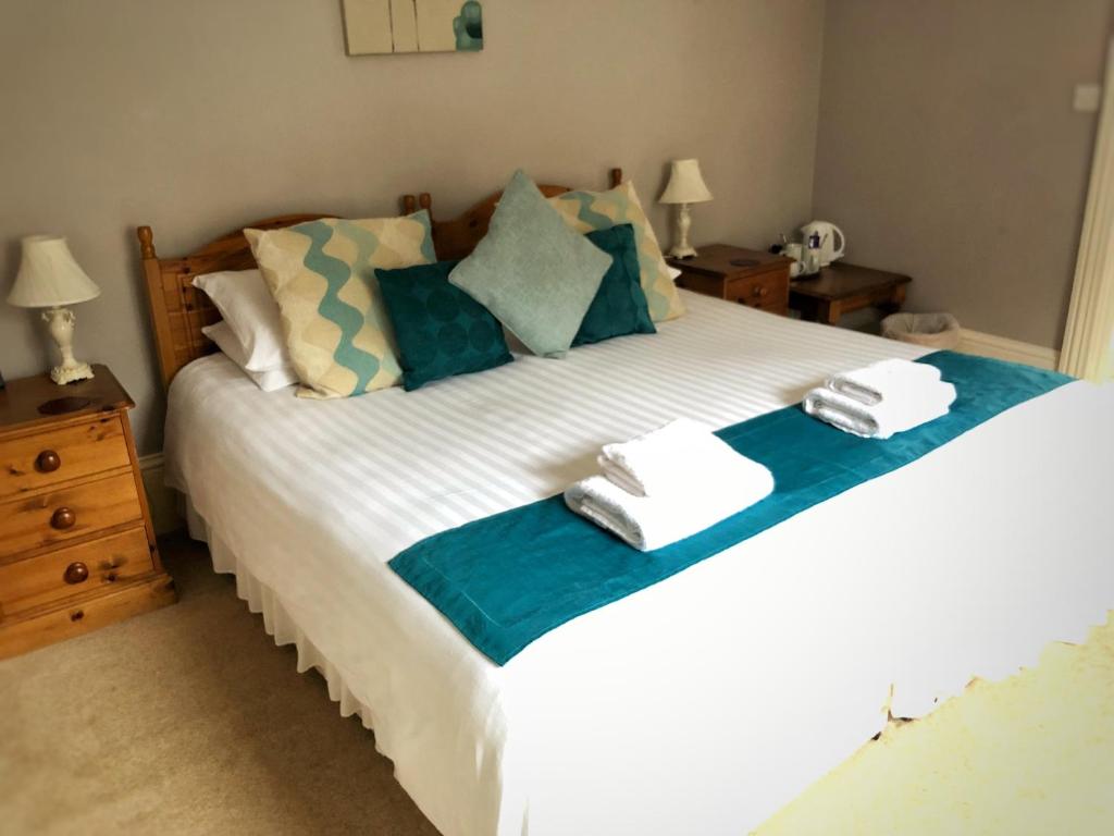 a bedroom with a large white bed with towels on it at The Riverside in Boscastle