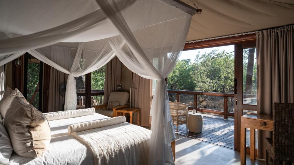 une chambre avec un lit à baldaquin et un balcon dans l'établissement Tuli Safari Lodge Mashatu, à Lentswelemoriti