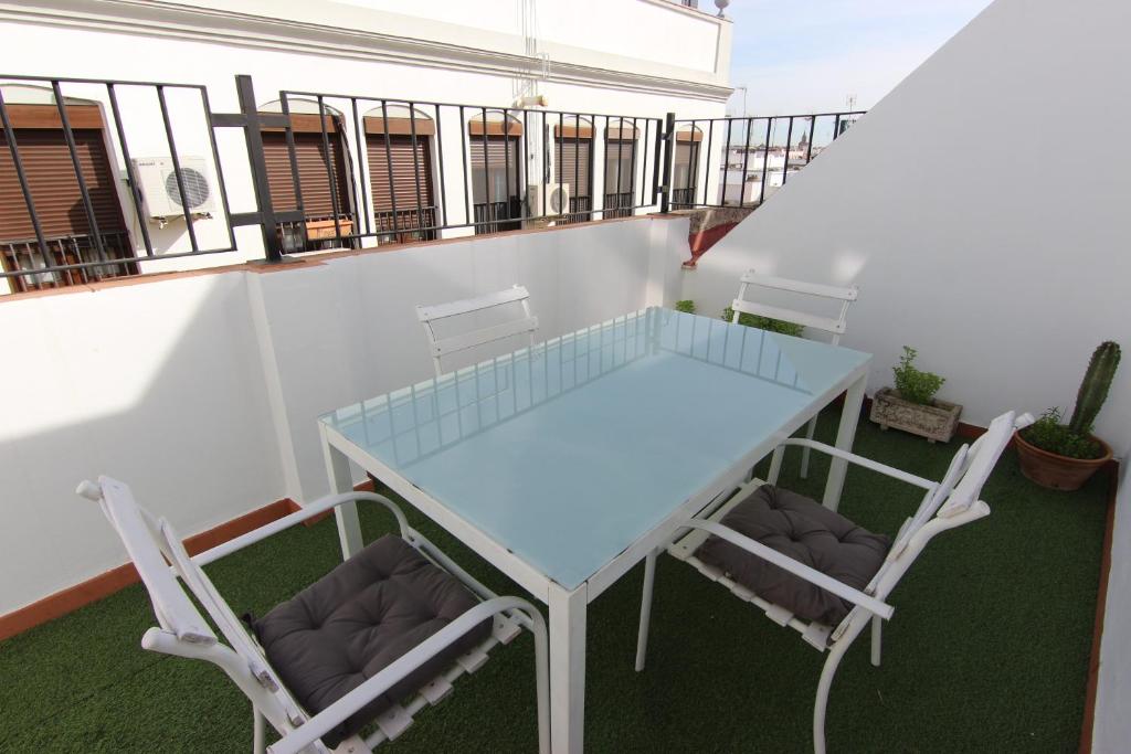 - Balcón con mesa de cristal y 2 sillas en RentalSevilla terraza privada junto al Guadalquivir, en Sevilla