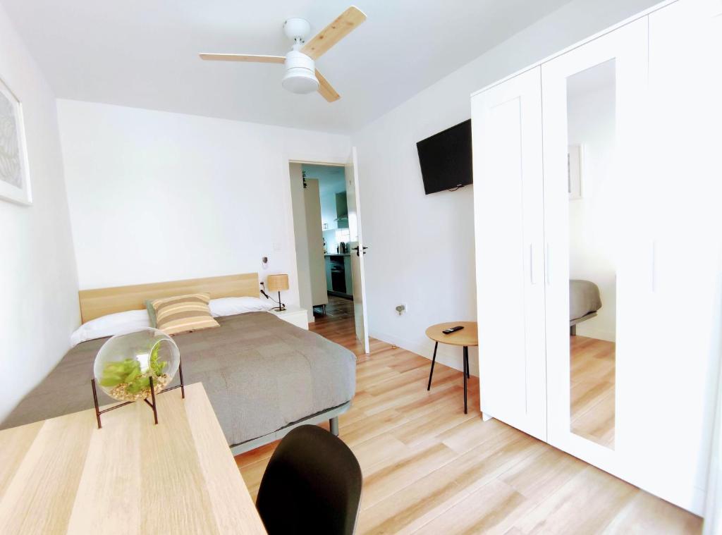 a white bedroom with a bed and a table at Habitaciones Santiago in Puerto de Sagunto