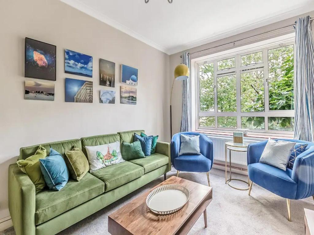 a living room with a green couch and two blue chairs at Pass the Keys Battersea Hideaway in London