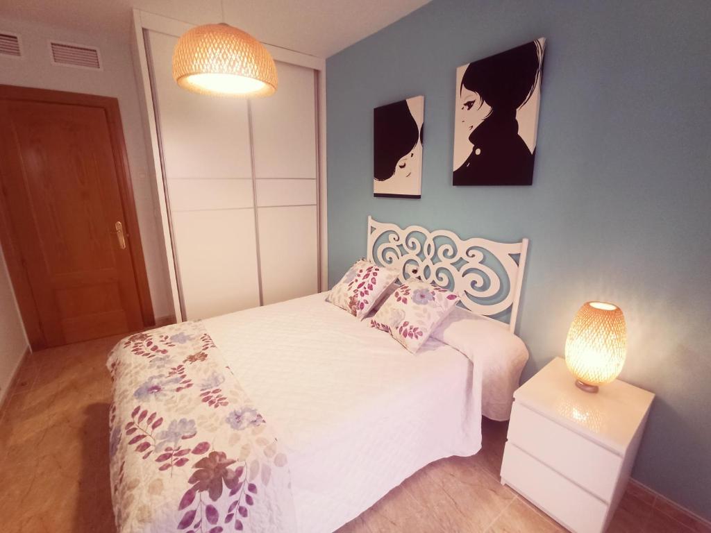 a bedroom with a white bed and two pictures on the wall at Playa de Levante, Céntrico, AC, Wifi y Parking - by Aloha Palma in Águilas