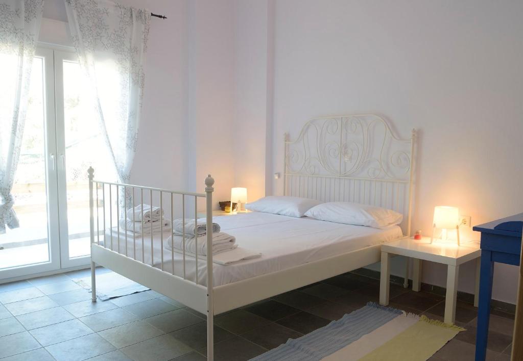 1 dormitorio con cama blanca y ventana en Melinda Holiday House en Plomari