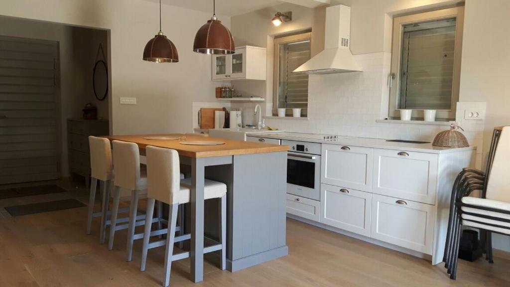 a kitchen with white cabinets and a wooden table at Villa Arbatica in Barbat na Rabu