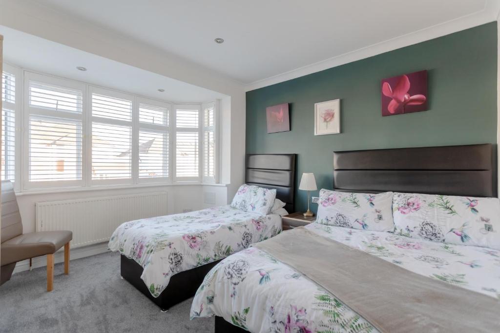 two beds in a bedroom with green walls at Room in Guest room - Apple House Wembley - Family room with shared bathroom in Edgware