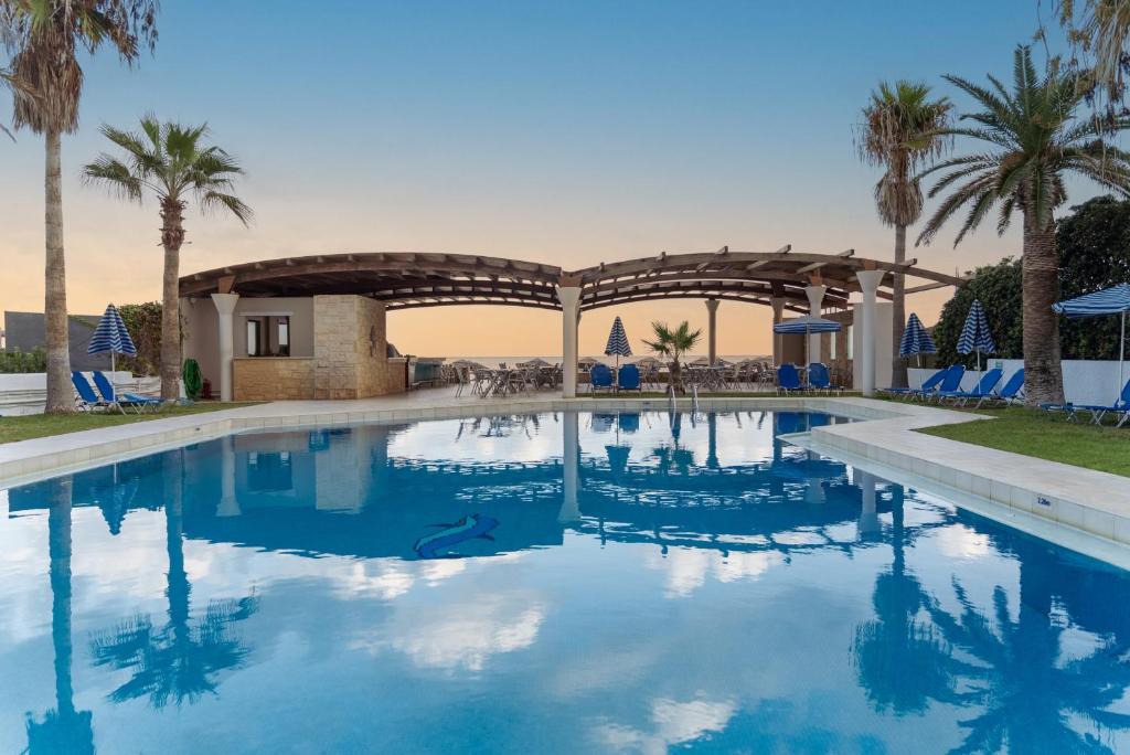 a swimming pool in a resort with palm trees at Eva Bay Hotel On The Beach - Adults Only in Adelianos Kampos