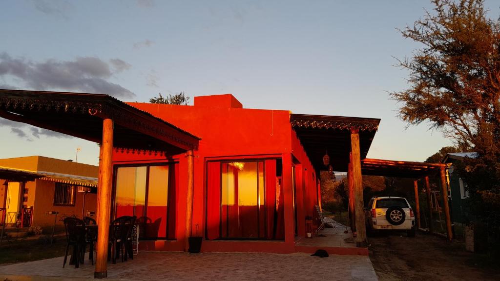 czerwony dom z samochodem zaparkowanym przed nim w obiekcie Casa Nekay w mieście San Lorenzo