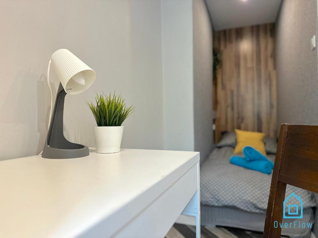 a white table with a lamp and a bedroom at Amber Studio in Gdańsk