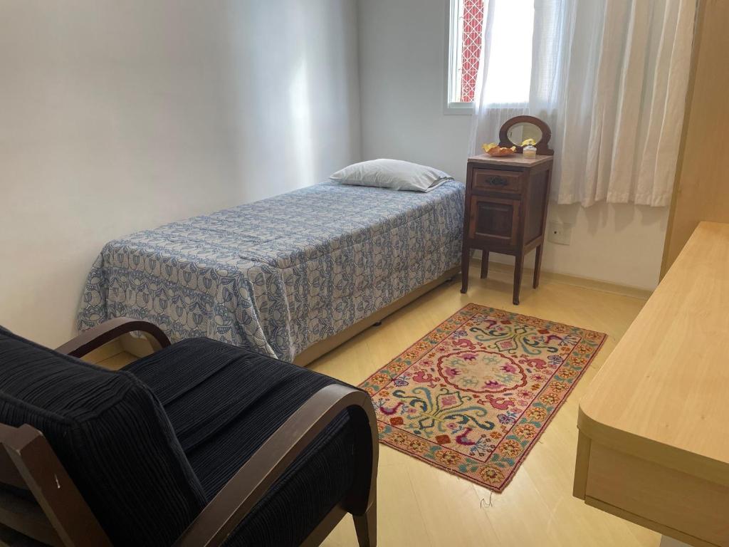 a bedroom with a bed and a chair and a rug at Quarto Morumbi - Somente Mulheres in Sao Paulo