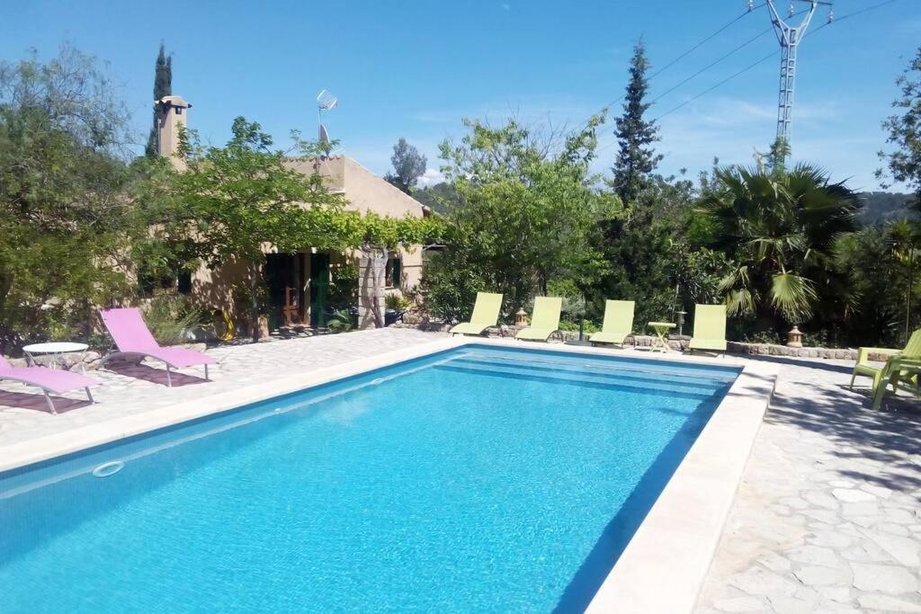 a swimming pool with chairs and a house at Sa Sort de Can Moix in Alaró