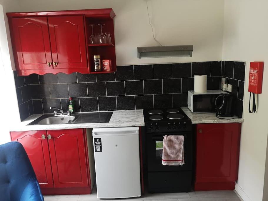 a small kitchen with red cabinets and a black stove at Ideal for short stays in Cork