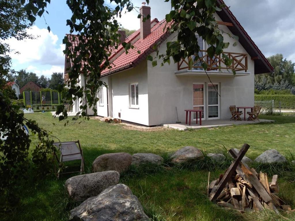 a white house with a red roof in a yard at House Hostelli in Grzybowo