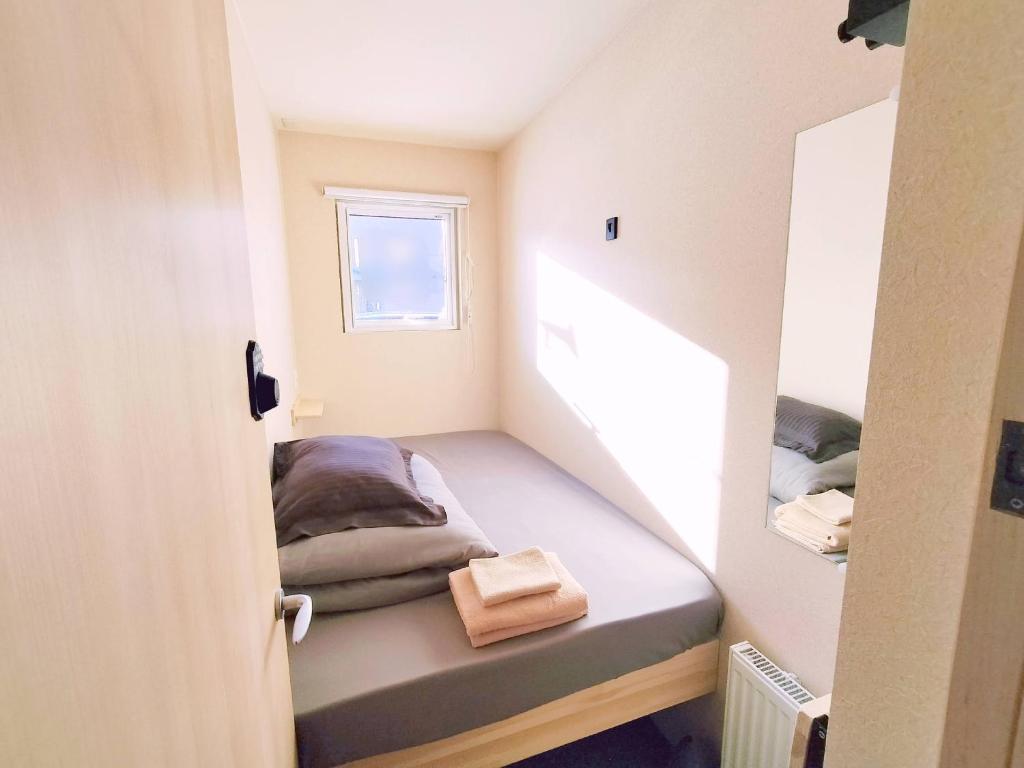 Habitación pequeña con cama y ventana en Sho inn MINIMAL HOTEL 小樽駅から無料送迎あり en Otaru