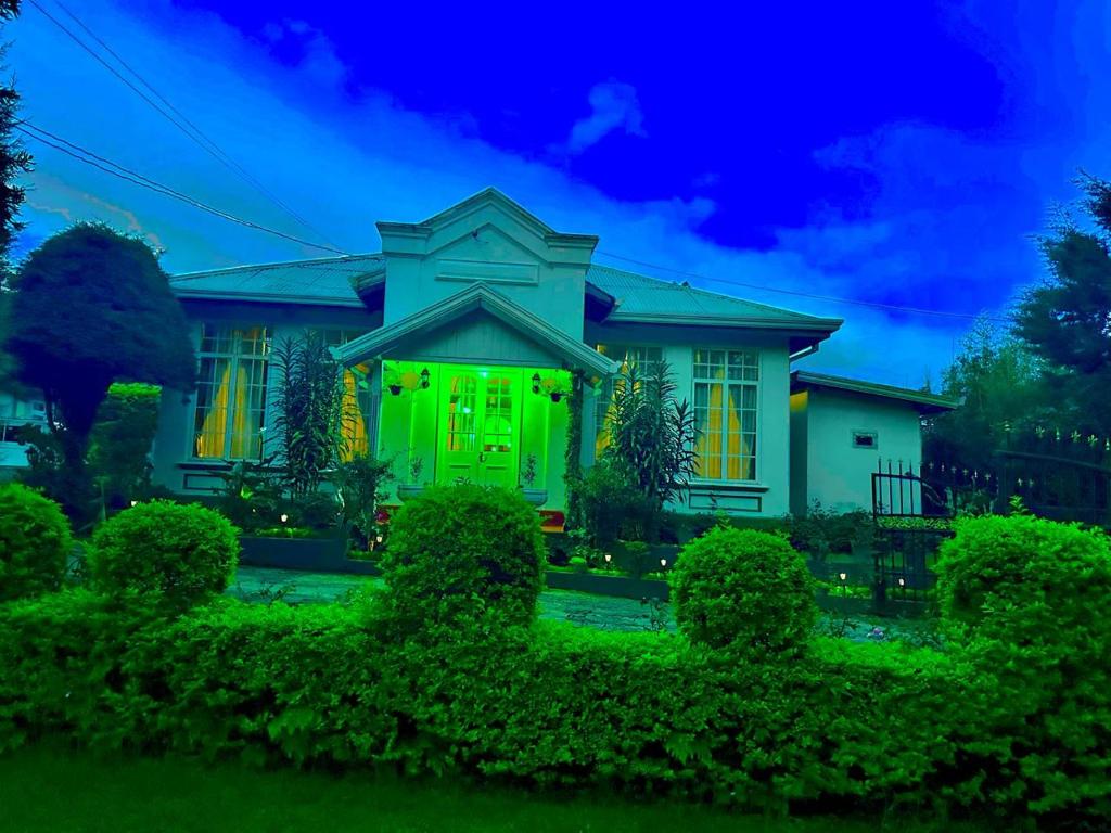 una casa con una puerta verde por la noche en Princess Bungalows, en Nuwara Eliya
