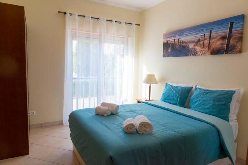 a bedroom with a blue bed with towels on it at TAC - Alcantarilha House in Alcantarilha