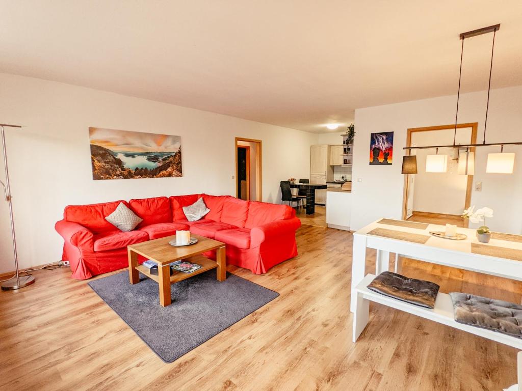 een woonkamer met een rode bank en een tafel bij Urlaubsmagie- Pool, Terrasse, Barbecue - W4 in Lichtenhain