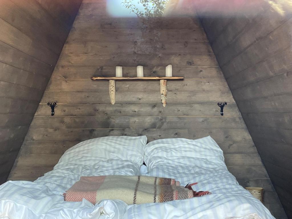 Bett in einem Zimmer mit Regal und Kerzen in der Unterkunft Glamping wooden house in Borgafjäll