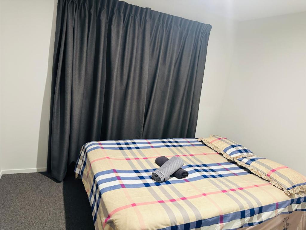 a bedroom with a bed with a plaid blanket at Private Double Room in Christchurch