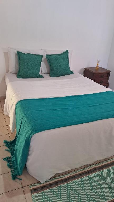 a large bed with green and white sheets and pillows at Chalé do riacho 1 in Itatiaia
