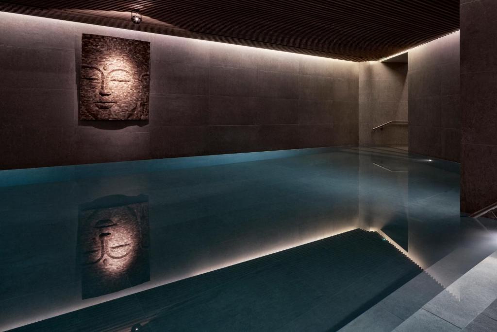a swimming pool with two statues of faces on the wall at The Margi in Athens