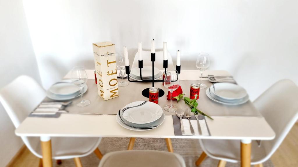 una mesa blanca con platos blancos y copas de vino en SMART-SCHÖN-Günstig,nähe U1 & Park and Ride ! en Viena