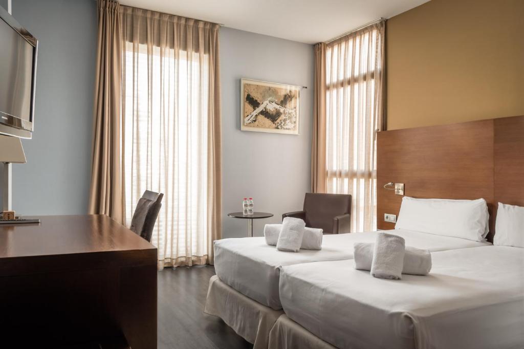 a hotel room with two beds and a desk at Hotel Madanis in Barcelona