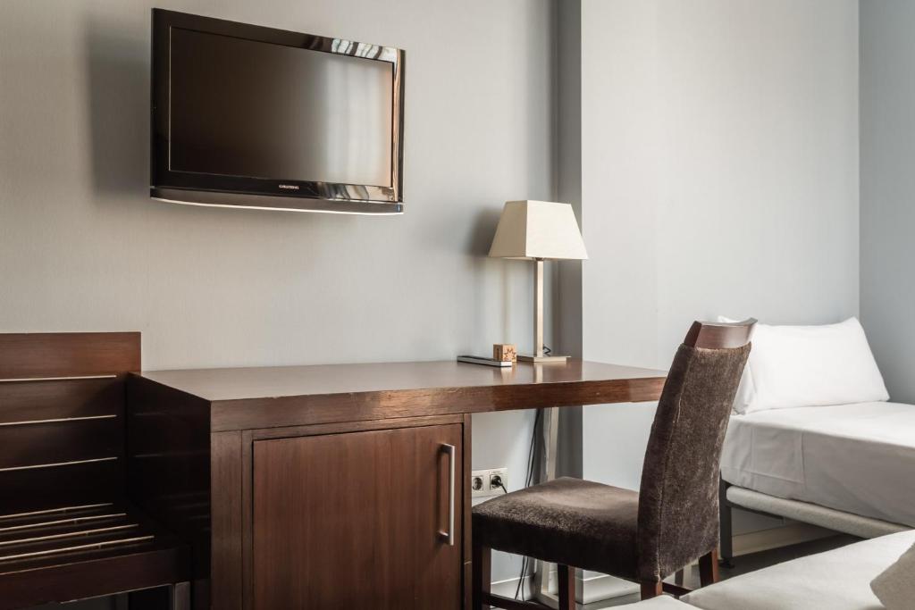 a hotel room with a desk with a tv and a bed at Hotel Madanis in Barcelona