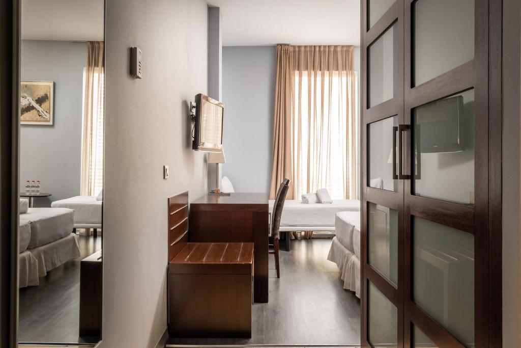 a hotel room with a desk and a bedroom at Hotel Madanis in Barcelona