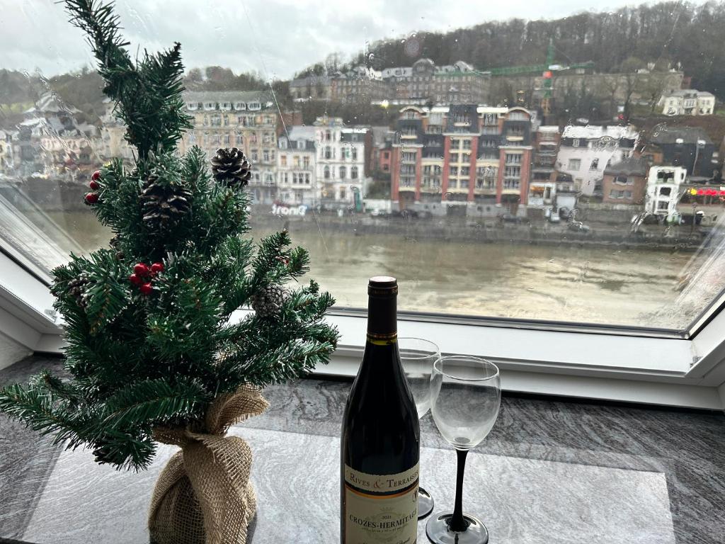 een fles wijn en twee glazen naast een raam bij Le Reflet Meuse in Dinant