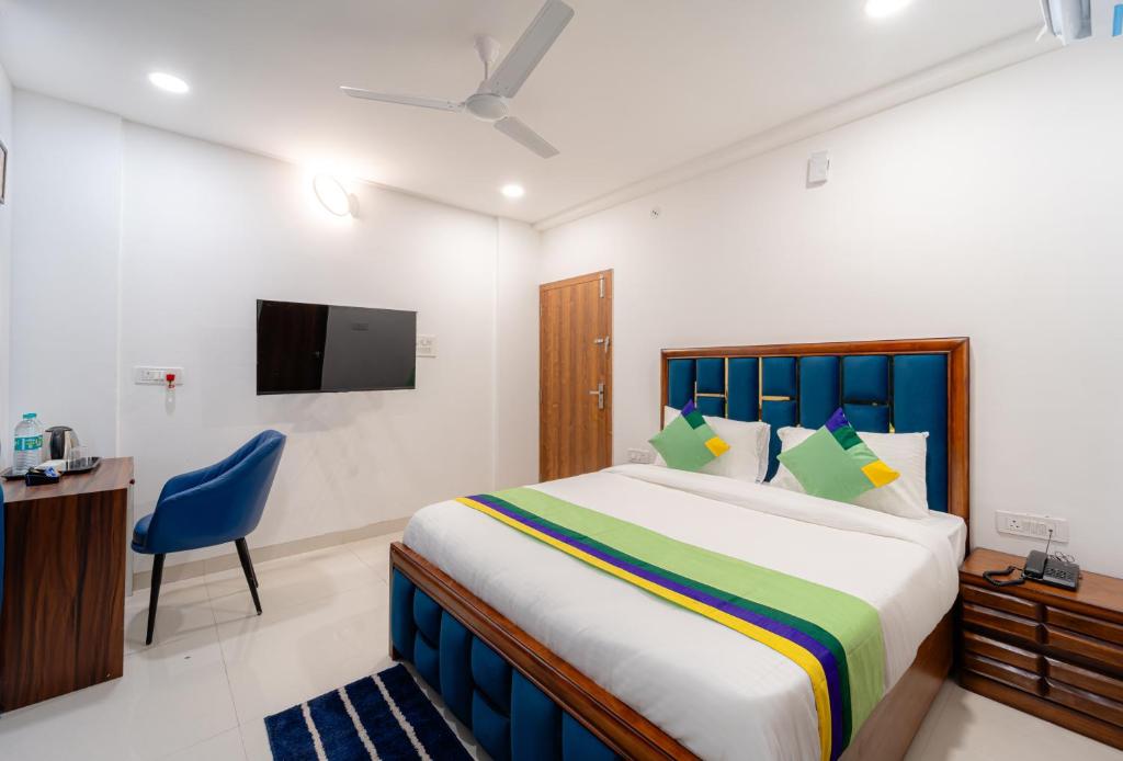 a bedroom with a bed and a chair and a tv at Treebo Trend Pure Earth Stay - Vijay Nagar in Indore