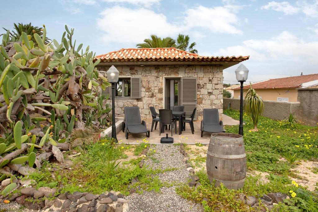 uma casa de pedra com uma mesa e cadeiras num quintal em Casa Do Vinho em Porto Santo