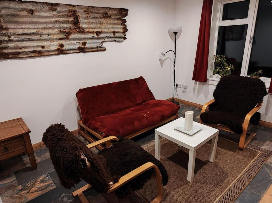 a living room with two chairs and a red couch at Kempies-Cozy house on the NC500 in Durness