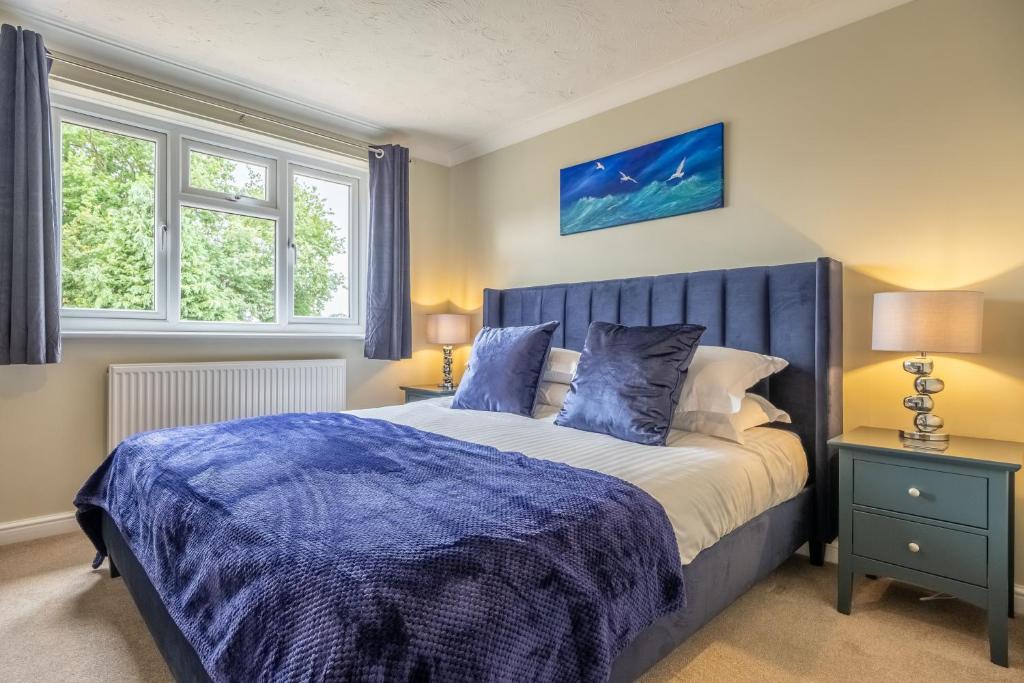sypialnia z łóżkiem z niebieską kołdrą i 2 oknami w obiekcie Langdale 4 w mieście Heacham