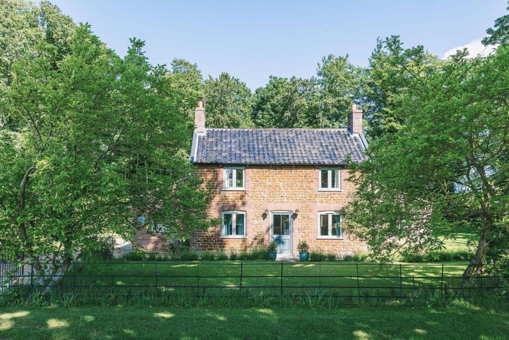 an old brick house with trees in front of it at Keepers Cottage F in Bircham Newton